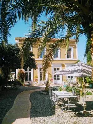 a house with a table and chairs and an umbrella at La Maison des Palmiers in Homps