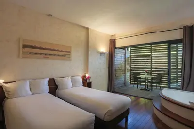 a hotel room with two beds and a balcony at Ile du Gua Suites in Narbonne