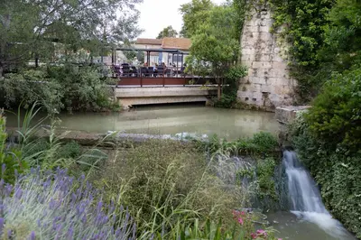 a bridge over a river with a waterfall at Ile du Gua Suites in Narbonne