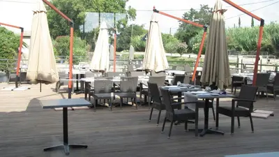 a restaurant with tables and chairs and umbrellas at Ile du Gua Suites in Narbonne