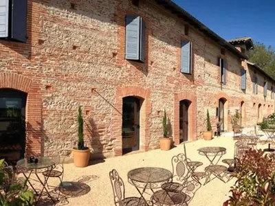 a brick building with tables and chairs in front of it at La Ferme O Délices in Mazères