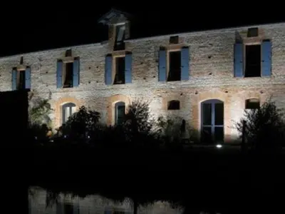 a large brick building with windows at night at La Ferme O Délices in Mazères