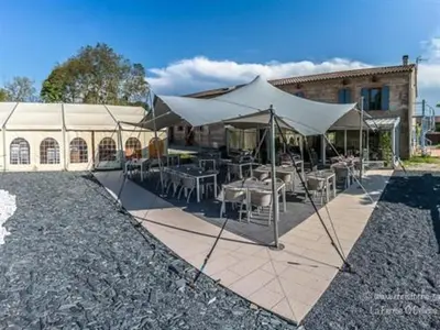 a tent with tables and chairs in front of a building at La Ferme O Délices in Mazères