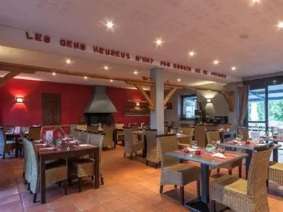 a dining room with tables and chairs in a restaurant at La Ferme O Délices in Mazères