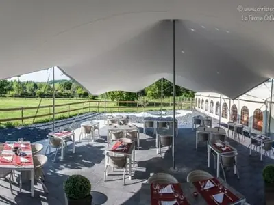 a patio with tables and chairs under an umbrella at La Ferme O Délices in Mazères