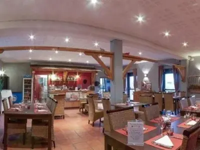 a dining room with tables and chairs in a restaurant at La Ferme O Délices in Mazères