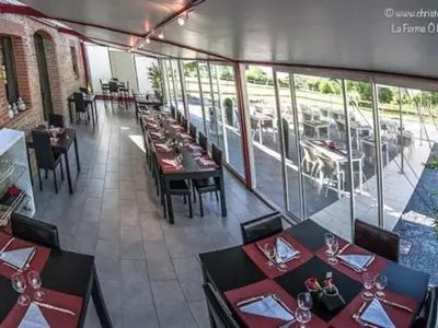 a dining room with tables and chairs in a restaurant at La Ferme O Délices in Mazères