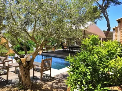 a pool with a tree and benches next to a house at Chambre d'Hôtes au Domaine du Soleil Couchant in Saint-André-de-Roquelongue