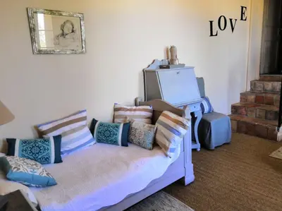 a room with a couch with pillows and a television at Chambre d'Hôtes au Domaine du Soleil Couchant in Saint-André-de-Roquelongue