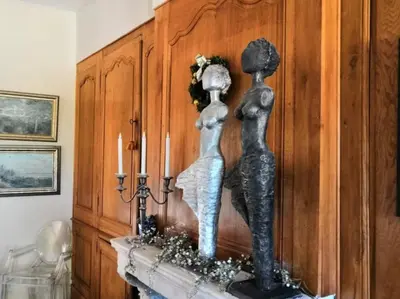 a statue of two women sitting on a fireplace at Chambre d'Hôtes au Domaine du Soleil Couchant in Saint-André-de-Roquelongue