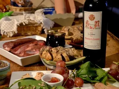 a table with a bottle of wine and a plate of food at Chambre d'Hôtes au Domaine du Soleil Couchant in Saint-André-de-Roquelongue