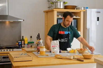 a man in a kitchen preparing food on a counter at Maison Rives - Village du Livre de Montolieu in Montolieu
