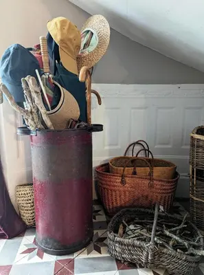 a red bucket filled with hats and baskets on a floor at Chateau de Thuries in Revel