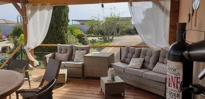 a patio with a couch and chairs on a deck at CHAMBRE D’HÔTES NATURE ET SAVEURS in Boutenac