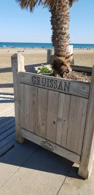 a wooden sign for a palm tree on the beach at CHAMBRE D’HÔTES NATURE ET SAVEURS in Boutenac