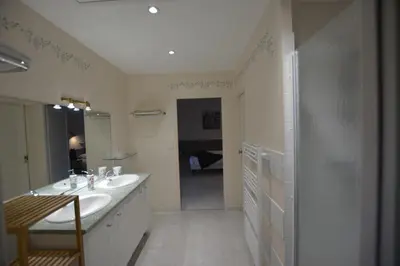 a white bathroom with two sinks and a shower at CHAMBRE D’HÔTES NATURE ET SAVEURS in Boutenac
