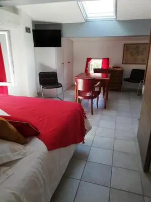 a bedroom with a red bed and a table and chairs at atmosphere in Poilhès