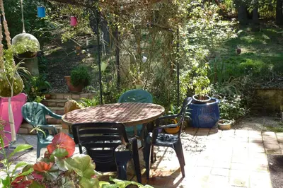 a patio with a table and chairs in a garden at LES BRUYERES chambre d'hôte de charme Calme assuré in Loupia