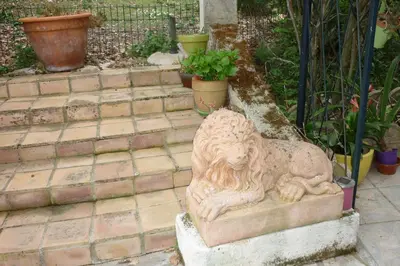 a stone lion statue sitting on a set of stairs at LES BRUYERES chambre d'hôte de charme Calme assuré in Loupia