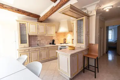 a large kitchen with wooden cabinets and a table at Appartement du Couvent in Narbonne