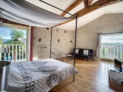 a bedroom with a bed and a large window at GITES STE CATHERINE in Teyssode