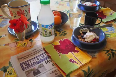 a table with a bowl of food and a bottle of milk at The Balcony Gîte - Riverside Lagrasse in Lagrasse