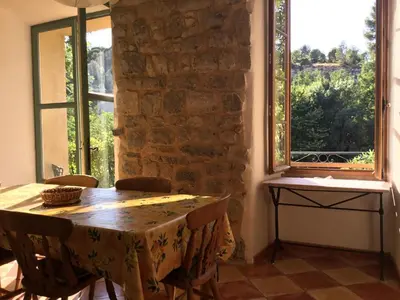 a dining room with a table and two windows at The Balcony Gîte - Riverside Lagrasse in Lagrasse