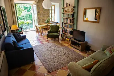 a living room with couches and a television and a table at The Balcony Gîte - Riverside Lagrasse in Lagrasse