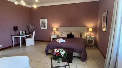 a bedroom with a bed and a table with flowers on it at Château La Sabine in Saint-Laurent-de-la-Cabrerisse