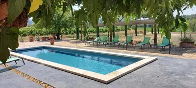 a swimming pool with green chairs next to a house at Château La Sabine in Saint-Laurent-de-la-Cabrerisse