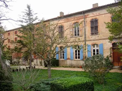 an old brick building with blue trim in a yard at Château de Vallègue in Vallègue