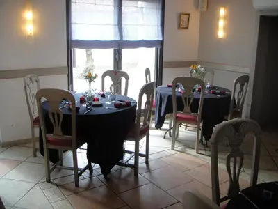 a dining room with two tables and chairs and a window at Auberge des Lices in Carcassonne