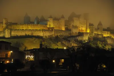 a large castle on top of a hill at night at Auberge des Lices in Carcassonne