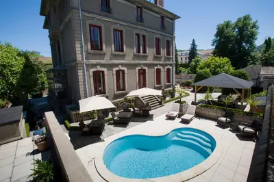 an outdoor swimming pool in front of a building at La Villa de Mazamet in Mazamet