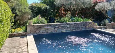 a swimming pool with a blue bench in a garden at Chambres d'hôtes Sous L'Olivier in Trausse
