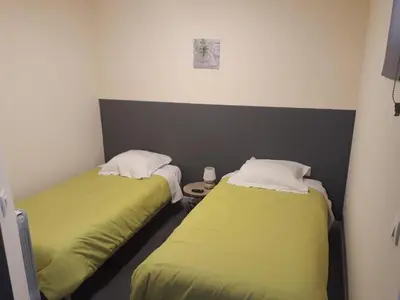 two beds in a room with green sheets at Hotel Motel Limoux in Limoux