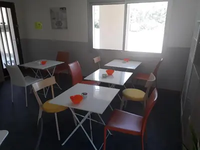 a room with tables and chairs and a window at Hotel Motel Limoux in Limoux