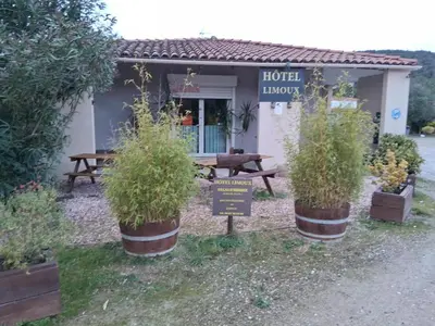 a restaurant with potted plants in front of a building at Hotel Motel Limoux in Limoux