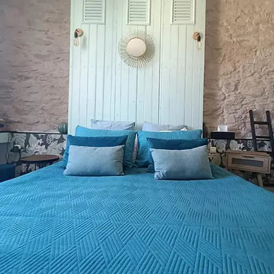 a blue bed with blue pillows in a bedroom at Entre Bastide et Cité et son rooftop in Carcassonne