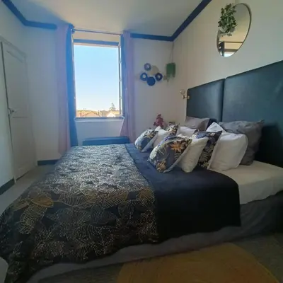 a bedroom with a large bed with a large window at Entre Bastide et Cité et son rooftop in Carcassonne