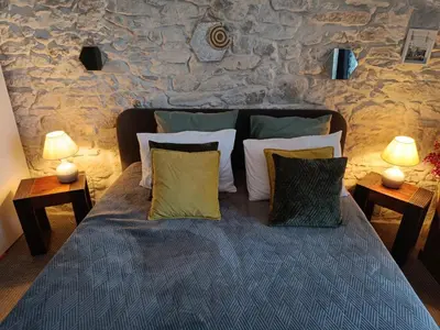 a bedroom with a bed with pillows and a stone wall at Entre Bastide et Cité et son rooftop in Carcassonne