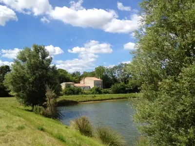 a river with a building in the middle of a field at Manoir enchanteur à Cailhau avec piscine privée sécurisée in Cailhau