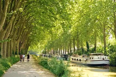 a tree lined canal with a boat and people walking down a path at Manoir enchanteur à Cailhau avec piscine privée sécurisée in Cailhau