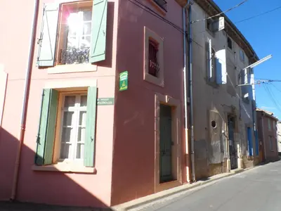a pink building with a garage and two windows at Clos Mazerolles in Cruzy