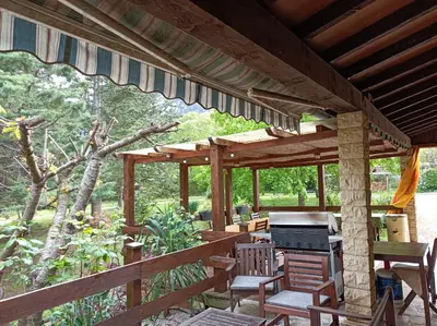a wooden pavilion with a table and chairs on a patio at Les Eaux Tranquilles in Belvianes-et-Cavirac