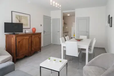 a living room with a table and chairs and a tv at Maison Borrel in Carcassonne