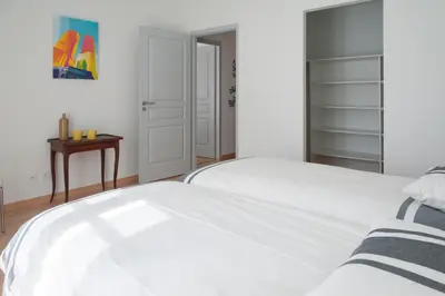 a white bedroom with a white bed and a table at Maison Borrel in Carcassonne