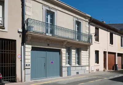 a building with a blue garage door and a balcony at Maison Borrel in Carcassonne