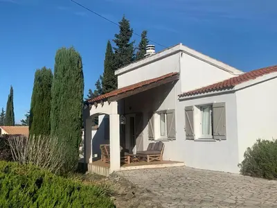 a white house with a porch with a chair at Villa in Pouzols with Private Pool & Vineyards in Pouzols-Minervois