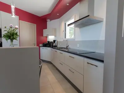 a kitchen with white cabinets and a red wall at Luxury villa with private pool in Cesseras in Cesseras